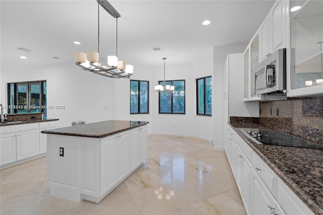 19347 SW 79th Pl, Cutler Bay, FL 33157 - kitchen featuring a chandelier, black electric cooktop, stainless steel microwave, tasteful backsplash, and glass insert cabinets