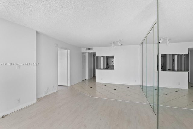 1865 Brickell Ave Unit A1204, Miami, FL 33129 - unfurnished living room featuring track lighting, light wood-type flooring, a textured ceiling, and baseboards