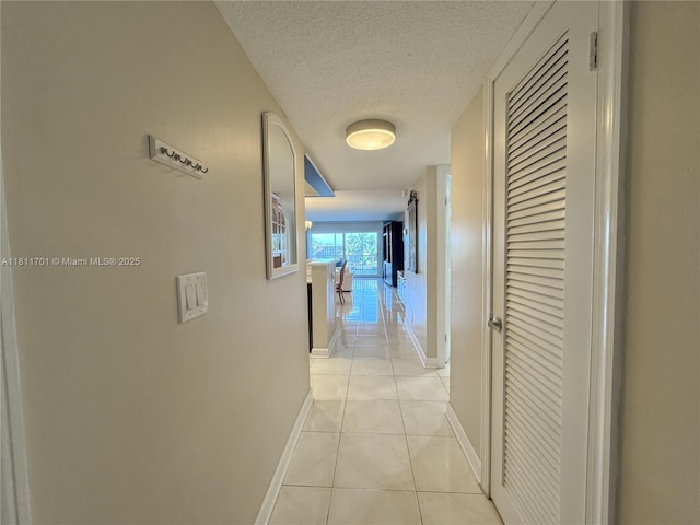 2097 S Ocean Dr Unit 302, Hallandale Beach, FL 33009 - corridor with baseboards, a textured ceiling, and light tile patterned flooring