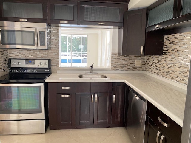 3660 NE 166th St Unit 115, North Miami Beach, FL 33160 - kitchen with stainless steel appliances, a sink, light tile patterned floors, decorative backsplash, and light countertops
