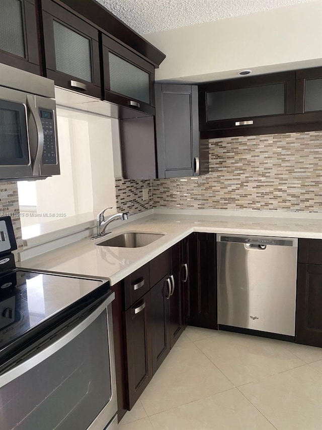 3660 NE 166th St Unit 115, North Miami Beach, FL 33160 - kitchen with appliances with stainless steel finishes, a sink, decorative backsplash, light tile patterned floors, and a textured ceiling