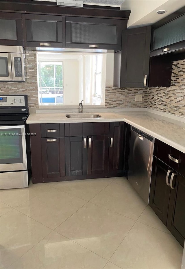 3660 NE 166th St Unit 115, North Miami Beach, FL 33160 - kitchen featuring stainless steel appliances, a sink, decorative backsplash, and light tile patterned floors