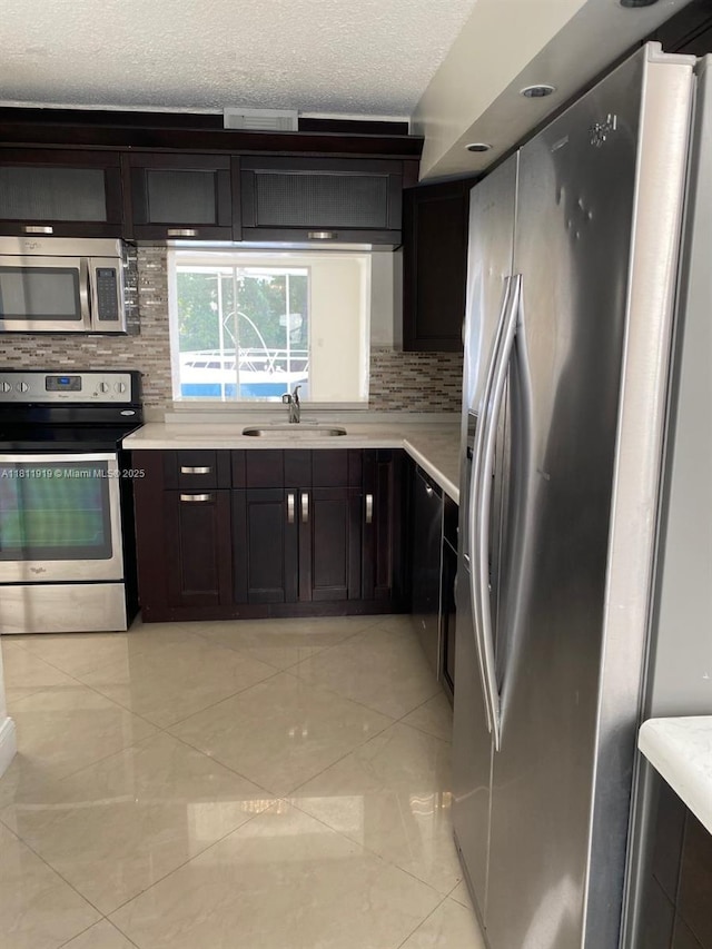 3660 NE 166th St Unit 115, North Miami Beach, FL 33160 - kitchen featuring stainless steel appliances, a sink, decorative backsplash, light countertops, and a textured ceiling