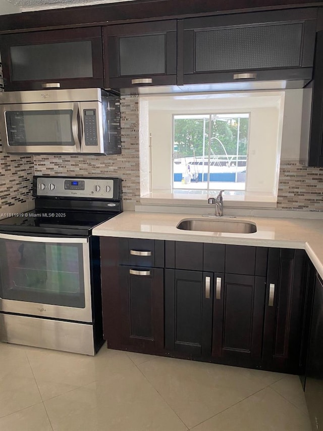 3660 NE 166th St Unit 115, North Miami Beach, FL 33160 - kitchen featuring stainless steel appliances, a sink, light tile patterned floors, backsplash, and light countertops