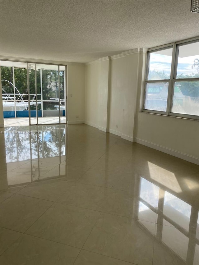 3660 NE 166th St Unit 115, North Miami Beach, FL 33160 - tiled empty room with a textured ceiling and baseboards