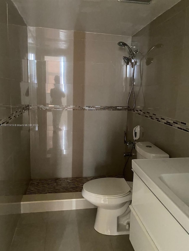 3660 NE 166th St Unit 115, North Miami Beach, FL 33160 - bathroom with toilet, tiled shower, vanity, tile patterned floors, and tile walls