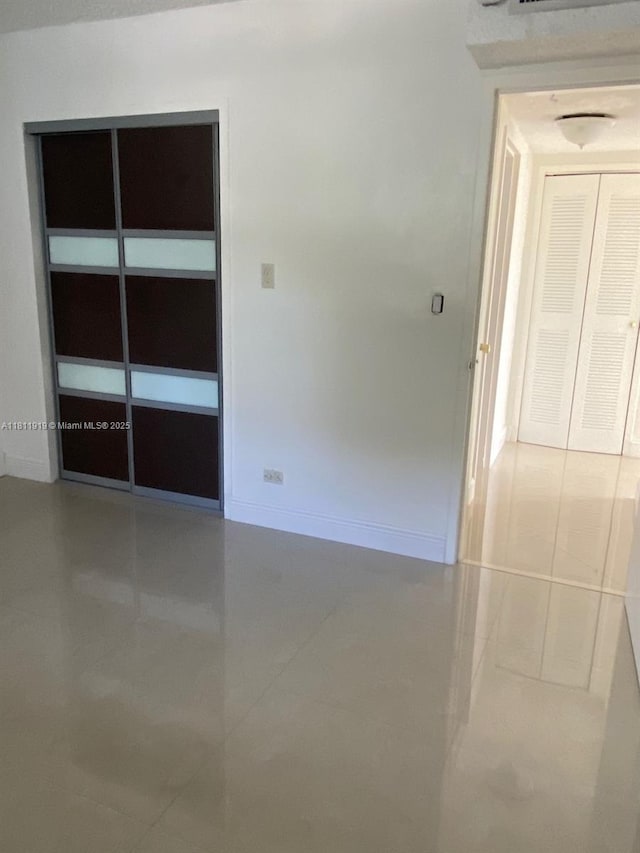 3660 NE 166th St Unit 115, North Miami Beach, FL 33160 - tiled empty room featuring baseboards