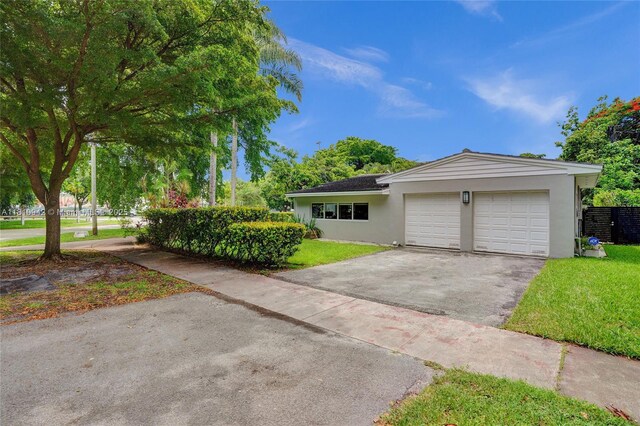 5620 Alhambra Cir, Coral Gables, FL 33146 - view of front facade with asphalt driveway, stucco siding, an attached garage, and a front yard