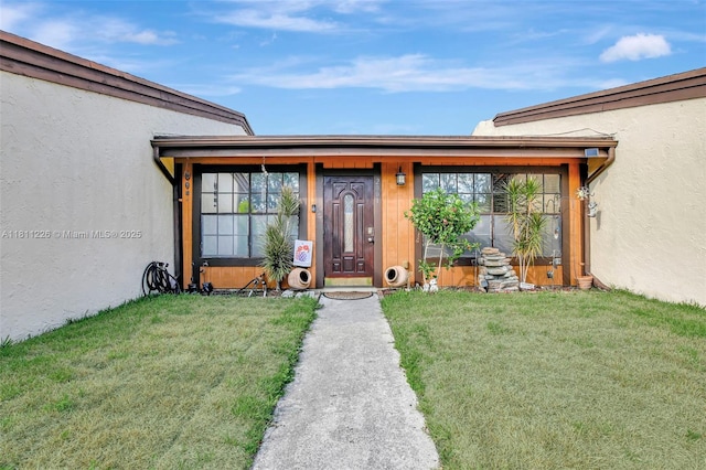 2001 Seagrape Ave, Pembroke Pines, FL 33026 - view of exterior entry with stucco siding, a lawn, and a porch