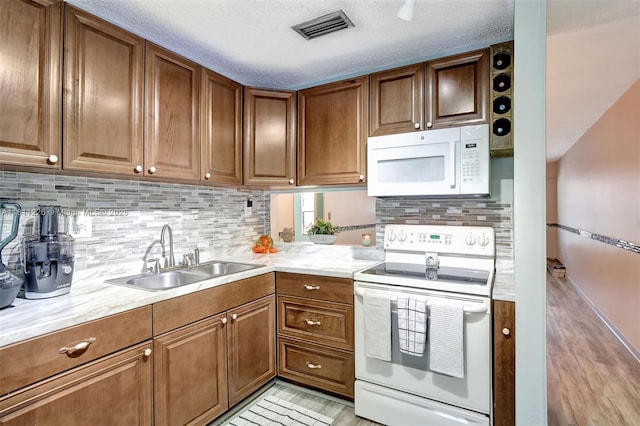 2001 Seagrape Ave, Pembroke Pines, FL 33026 - kitchen featuring white appliances, a sink, brown cabinetry, and decorative backsplash