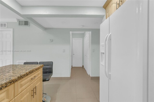 17101 NW 57th Ave Unit 110, Miami Gardens, FL 33055 - kitchen with white refrigerator with ice dispenser, light brown cabinetry, baseboards, light tile patterned floors, and light stone counters