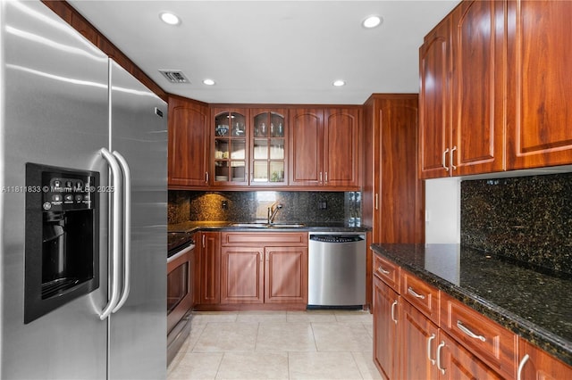 1950 S Ocean Dr Unit 7F, Hallandale Beach, FL 33009 - kitchen featuring stainless steel appliances, a sink, dark stone counters, light tile patterned floors, and glass insert cabinets