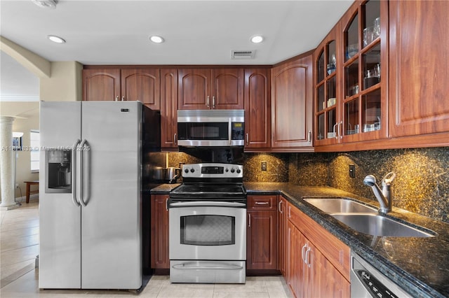 1950 S Ocean Dr Unit 7F, Hallandale Beach, FL 33009 - kitchen featuring stainless steel appliances, decorative columns, a sink, dark stone counters, and glass insert cabinets