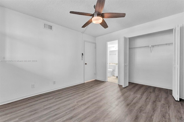 2525 Florida Blvd Unit 530, Delray Beach, FL 33483 - unfurnished bedroom featuring a textured ceiling, wood finished floors, ensuite bathroom, a closet, and a ceiling fan