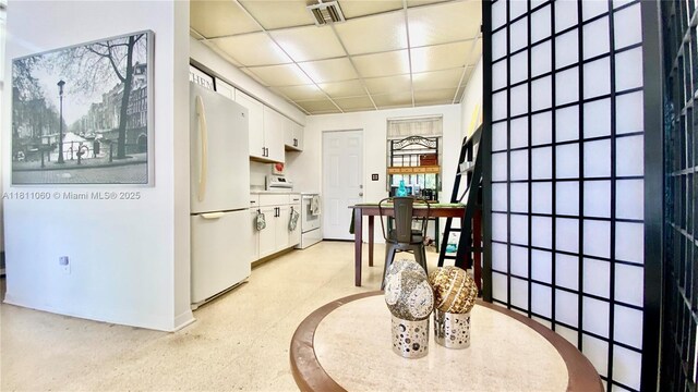 580 NE 139th St, North Miami, FL 33161 - kitchen featuring white appliances, white cabinetry, a paneled ceiling, and baseboards
