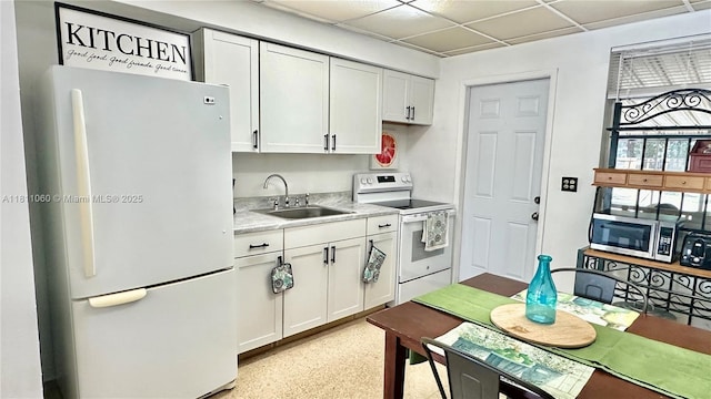 580 NE 139th St, North Miami, FL 33161 - kitchen with white appliances, a sink, light countertops, white cabinets, and a paneled ceiling