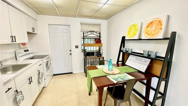 580 NE 139th St, North Miami, FL 33161 - kitchen featuring white range with electric cooktop, a paneled ceiling, white cabinetry, a sink, and light countertops