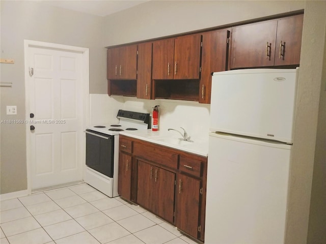 580 NE 139th St, North Miami, FL 33161 - kitchen featuring freestanding refrigerator, range with electric cooktop, light countertops, a sink, and light tile patterned floors