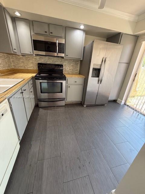 9423 NW 65th St Unit E2, Tamarac, FL 33321 - kitchen featuring appliances with stainless steel finishes, crown molding, decorative backsplash, dark wood finished floors, and gray cabinets
