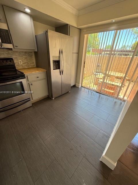 9423 NW 65th St Unit E2, Tamarac, FL 33321 - kitchen with appliances with stainless steel finishes, crown molding, light countertops, backsplash, and white cabinetry