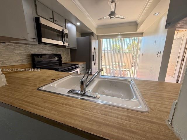9423 NW 65th St Unit E2, Tamarac, FL 33321 - kitchen featuring appliances with stainless steel finishes, ornamental molding, a sink, backsplash, and light countertops