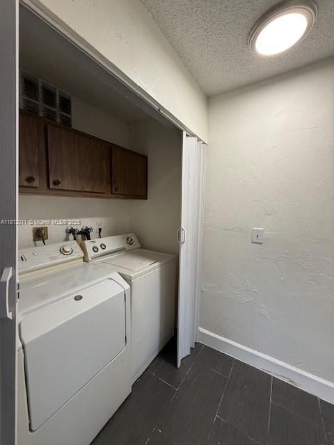 9423 NW 65th St Unit E2, Tamarac, FL 33321 - washroom featuring cabinet space, washing machine and dryer, baseboards, and a textured ceiling