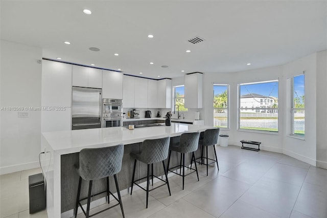 16880 SW 49th Ct, Miramar, FL 33027 - kitchen featuring stainless steel appliances, a sink, a large island, white cabinetry, and light countertops