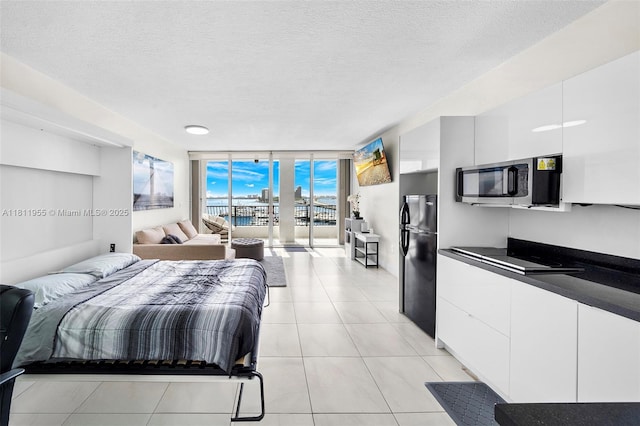 555 NE 15th St Unit 516, Miami, FL 33132 - bedroom with freestanding refrigerator, expansive windows, a textured ceiling, access to outside, and light tile patterned floors
