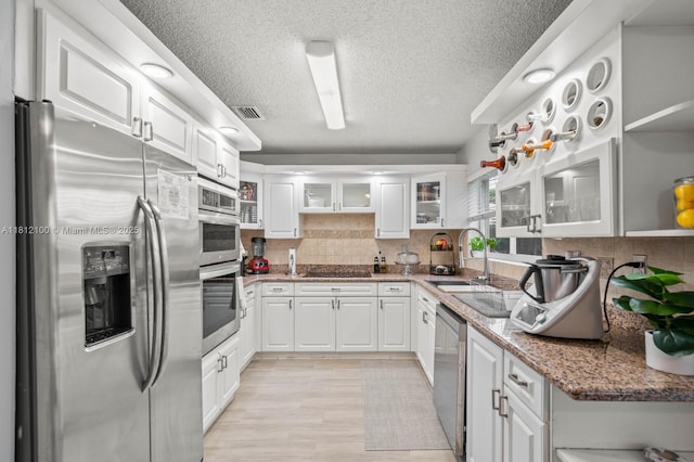 7251 SW 158th Pl, Miami, FL 33193 - kitchen with stainless steel appliances, a textured ceiling, white cabinets, backsplash, and glass insert cabinets