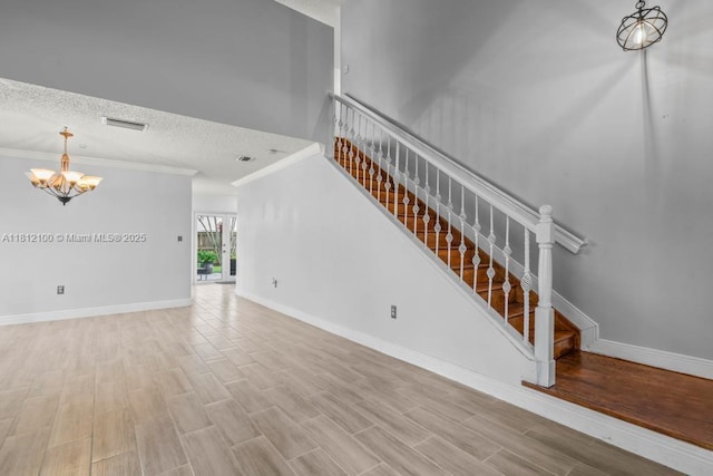 7251 SW 158th Pl, Miami, FL 33193 - unfurnished living room featuring a chandelier, stairs, ornamental molding, wood finished floors, and a textured ceiling
