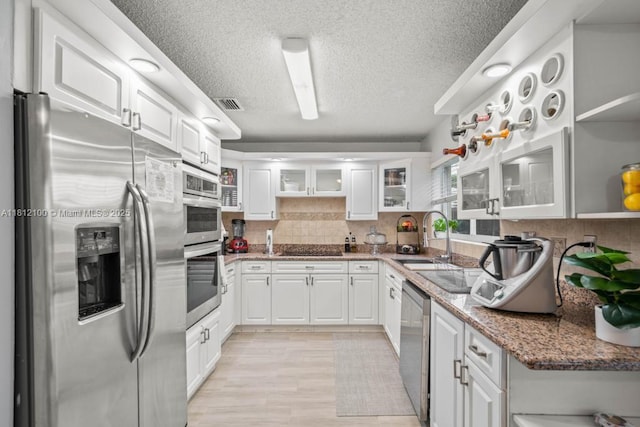 7251 SW 158th Pl, Miami, FL 33193 - kitchen with stainless steel appliances, a textured ceiling, white cabinetry, and decorative backsplash