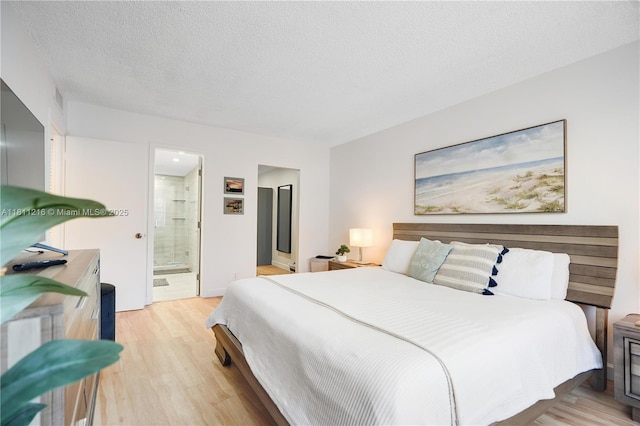 401 Golden Isles Dr Unit 302, Hallandale Beach, FL 33009 - bedroom with ensuite bathroom, light wood finished floors, and a textured ceiling