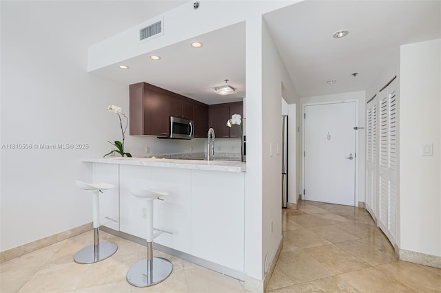 3001 SW 27th Ave Unit 201, Miami, FL 33133 - kitchen featuring appliances with stainless steel finishes, light countertops, baseboards, recessed lighting, and dark brown cabinets