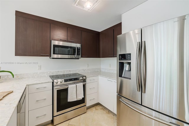 3001 SW 27th Ave Unit 201, Miami, FL 33133 - kitchen with appliances with stainless steel finishes, dark brown cabinets, light tile patterned floors, white cabinets, and light stone counters