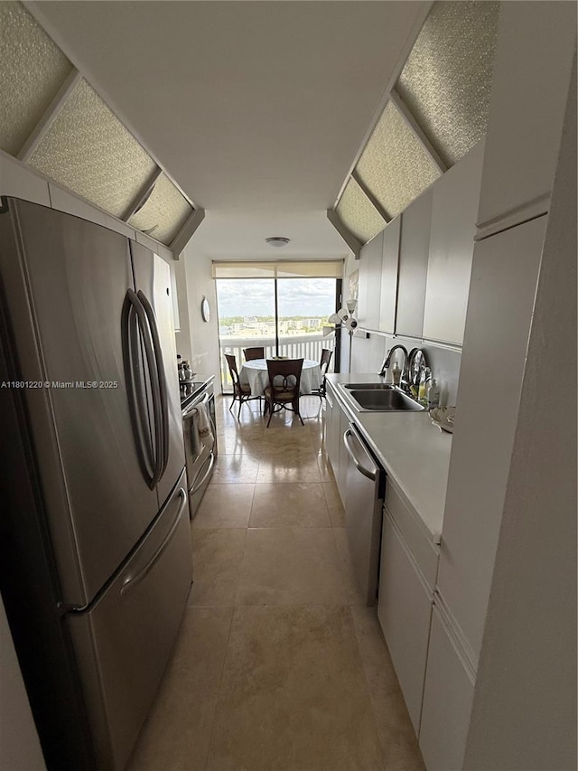 1000 Island Blvd Unit 911, Aventura, FL 33160 - kitchen featuring stainless steel appliances, a sink, white cabinets, light countertops, and a wall of windows