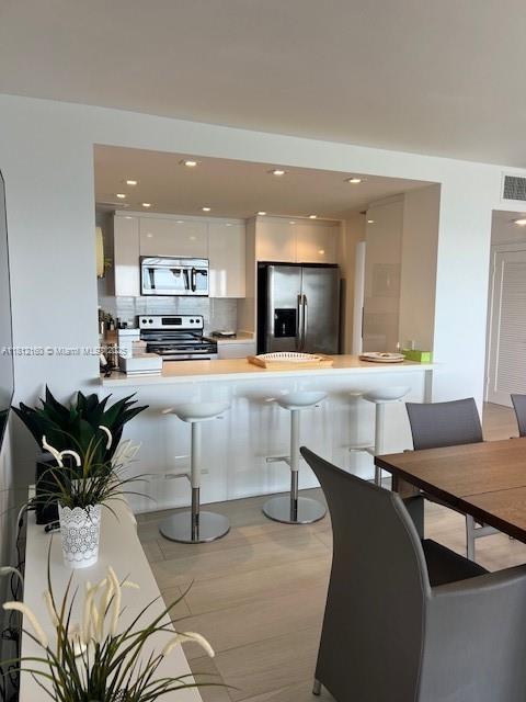 11111 Biscayne Blvd Unit 8C, Miami, FL 33181 - kitchen featuring stainless steel appliances, modern cabinets, a peninsula, white cabinets, and light countertops