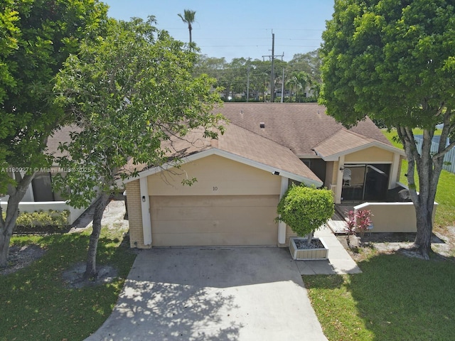 10 Afton Pl, Boynton Beach, FL 33426 - view of property hidden behind natural elements featuring driveway, an attached garage, roof with shingles, and a front lawn
