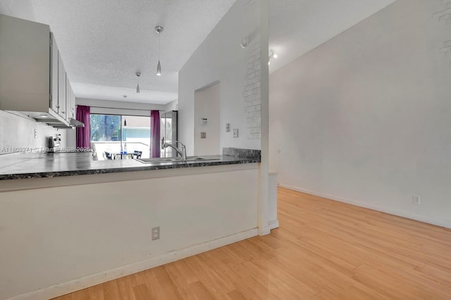 10 Afton Pl, Boynton Beach, FL 33426 - kitchen featuring light wood-type flooring, dark countertops, a sink, and baseboards