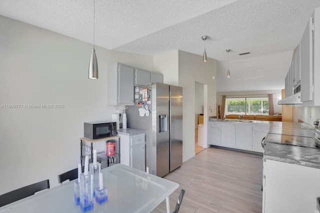 10 Afton Pl, Boynton Beach, FL 33426 - kitchen with stainless steel refrigerator with ice dispenser, black microwave, a textured ceiling, light wood-style floors, and a sink