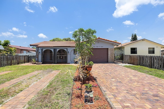 5808 Polk St, Hollywood, FL 33021 - mediterranean / spanish house featuring a tile roof, a garage, decorative driveway, and a fenced front yard