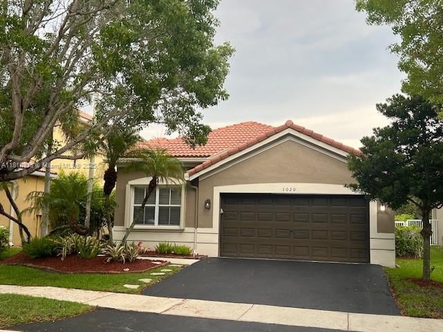 1020 Silktree Ln, Weston, FL 33327 - mediterranean / spanish-style home with a tile roof, an attached garage, stucco siding, and driveway