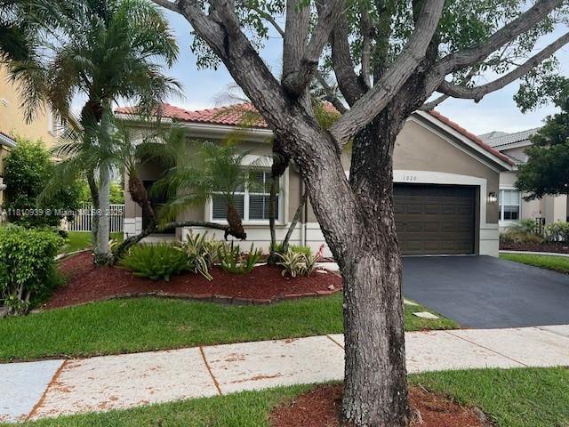 1020 Silktree Ln, Weston, FL 33327 - view of front of property with stucco siding, a tile roof, concrete driveway, and a garage