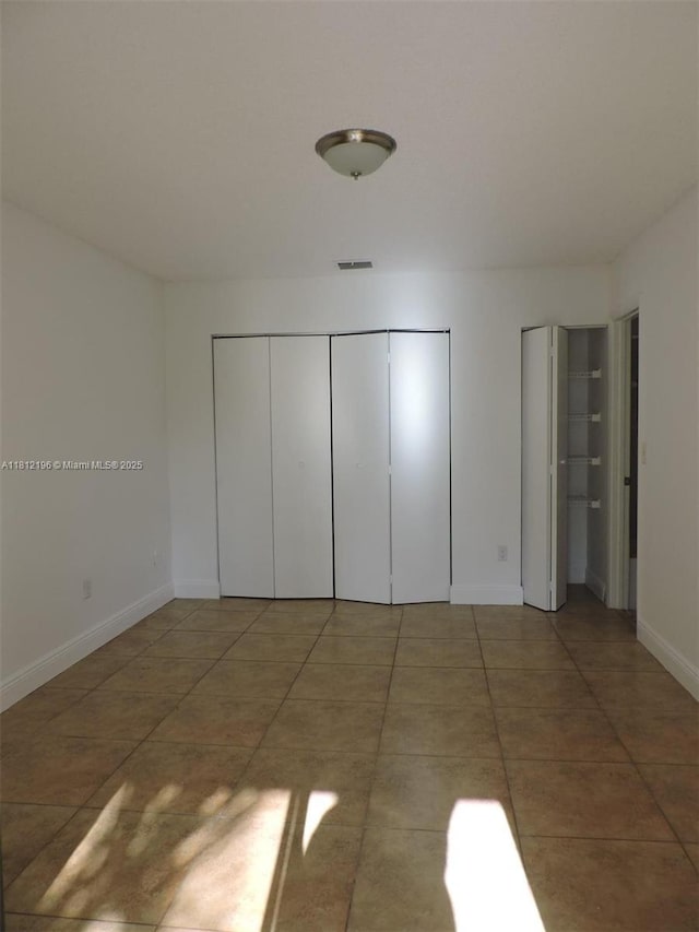 1331 S Franklin Ave Unit 1331E, Homestead, FL 33034 - unfurnished bedroom with baseboards, tile patterned floors, and multiple closets