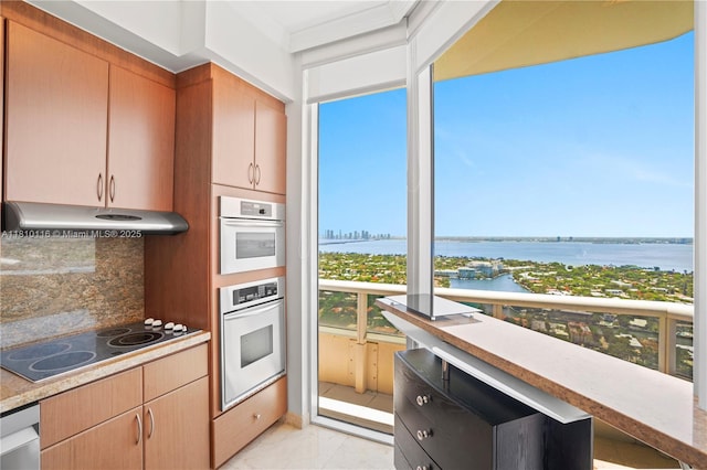 4775 Collins Ave Unit Ph4107, Miami Beach, FL 33140 - kitchen featuring stainless steel oven, under cabinet range hood, black electric cooktop, backsplash, and a water view
