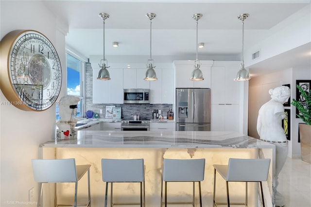 650 W Ave Unit Ph09, Miami Beach, FL 33139 - kitchen with appliances with stainless steel finishes, modern cabinets, white cabinetry, a breakfast bar area, and a peninsula