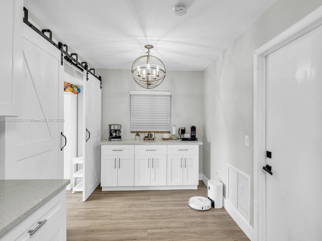 11610 NW 32nd Mnr, Sunrise, FL 33323 - laundry room featuring a barn door, light wood-style flooring, and a chandelier