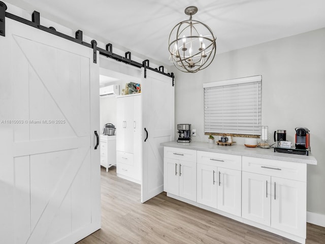 11610 NW 32nd Mnr, Sunrise, FL 33323 - kitchen featuring a barn door, light wood finished floors, white cabinetry, light countertops, and pendant lighting