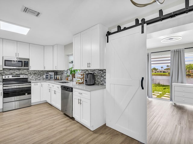 11610 NW 32nd Mnr, Sunrise, FL 33323 - kitchen with stainless steel appliances, light countertops, light wood finished floors, tasteful backsplash, and a barn door