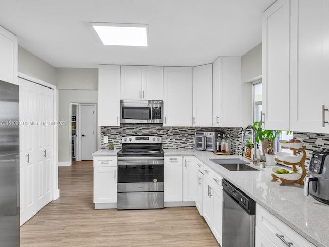 11610 NW 32nd Mnr, Sunrise, FL 33323 - kitchen featuring appliances with stainless steel finishes, a sink, decorative backsplash, white cabinets, and light stone countertops