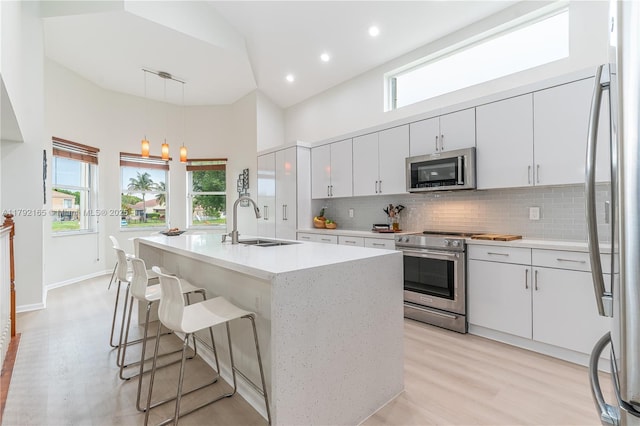 5064 SW 164th Ave, Miramar, FL 33027 - kitchen featuring appliances with stainless steel finishes, high vaulted ceiling, backsplash, light wood-style floors, and hanging light fixtures